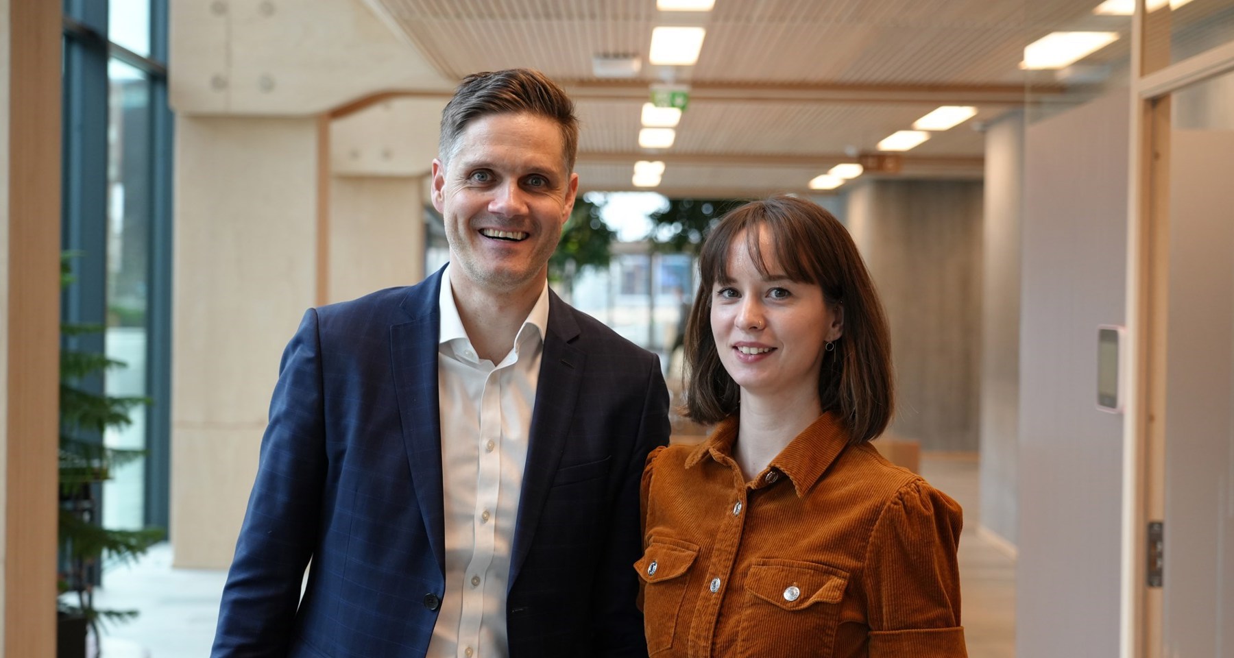 Ole Gilje og Mari Løvås i SpareBank 1 Sør-Norge står ved siden av hverandre på kontorlokaler.
