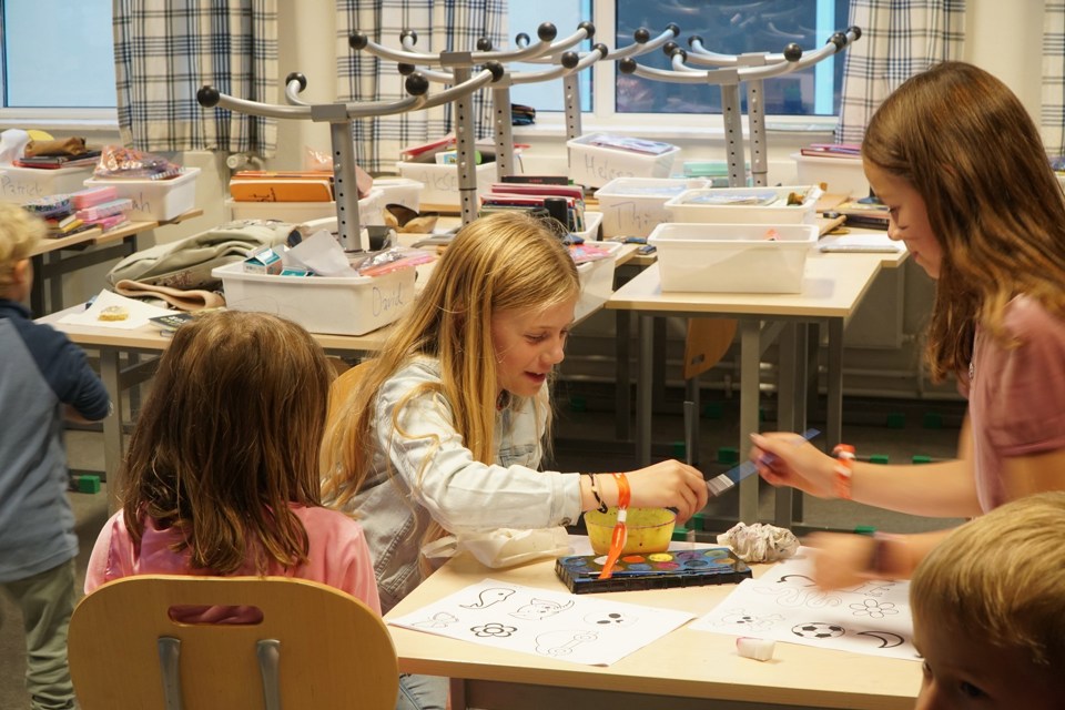 Tre barn maler i et klasserom. 
