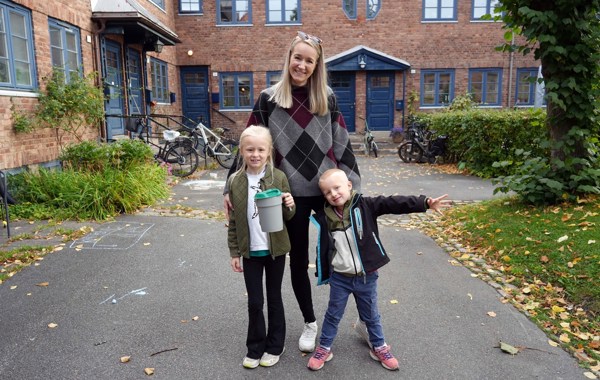 En mor og to barn står med bøsse i et nabolag.