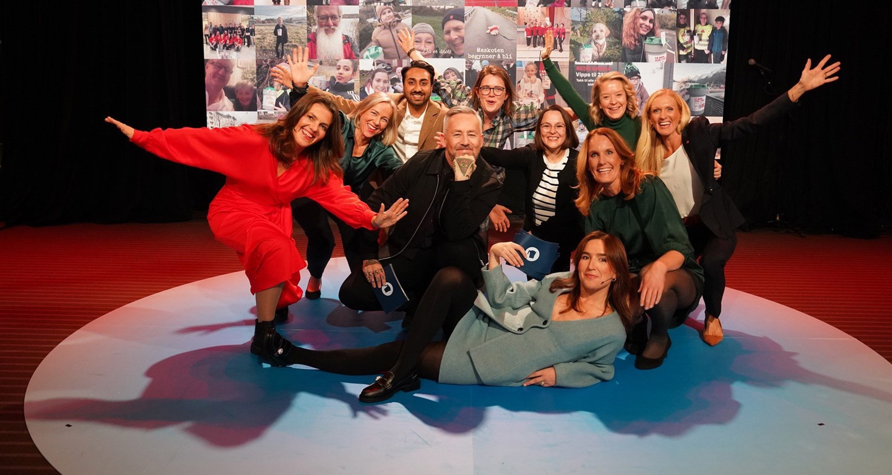 Programledere og deltakere fra TV-sendingen 2023 poserer sammen. Bak dem er en vegg med bilde av bøssebærere