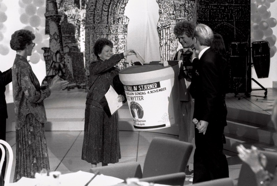 Gro Harlem Brundtland i studio i 1990, gir gave til TV-aksjonen på vegne av regjeringen. Hun putter en sjekk i en stor bøsse, og får applaus av folk rundt.