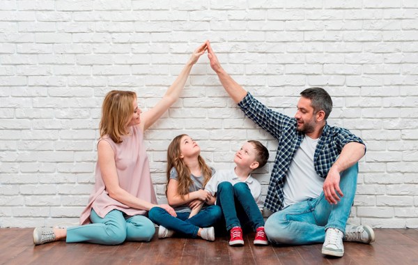 Familie Sitter Med Armer Som Tak Stock Photo